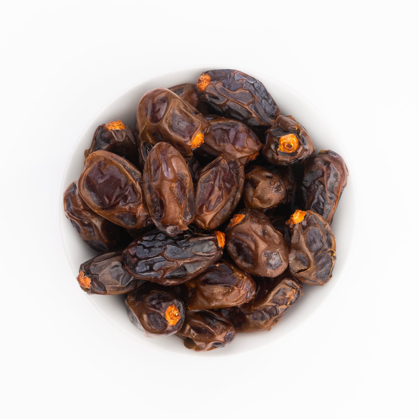 Blick von oben auf eine weiße Schale, gefüllt mit DATTELBAER Medjool Datteln BIO Choice - bissfest & klein. Die entsteinten, dunkelbraunen Datteln sind faltig, einige haben orangefarbene Stielreste. Abgebildet ist die 1 kg Packung.
